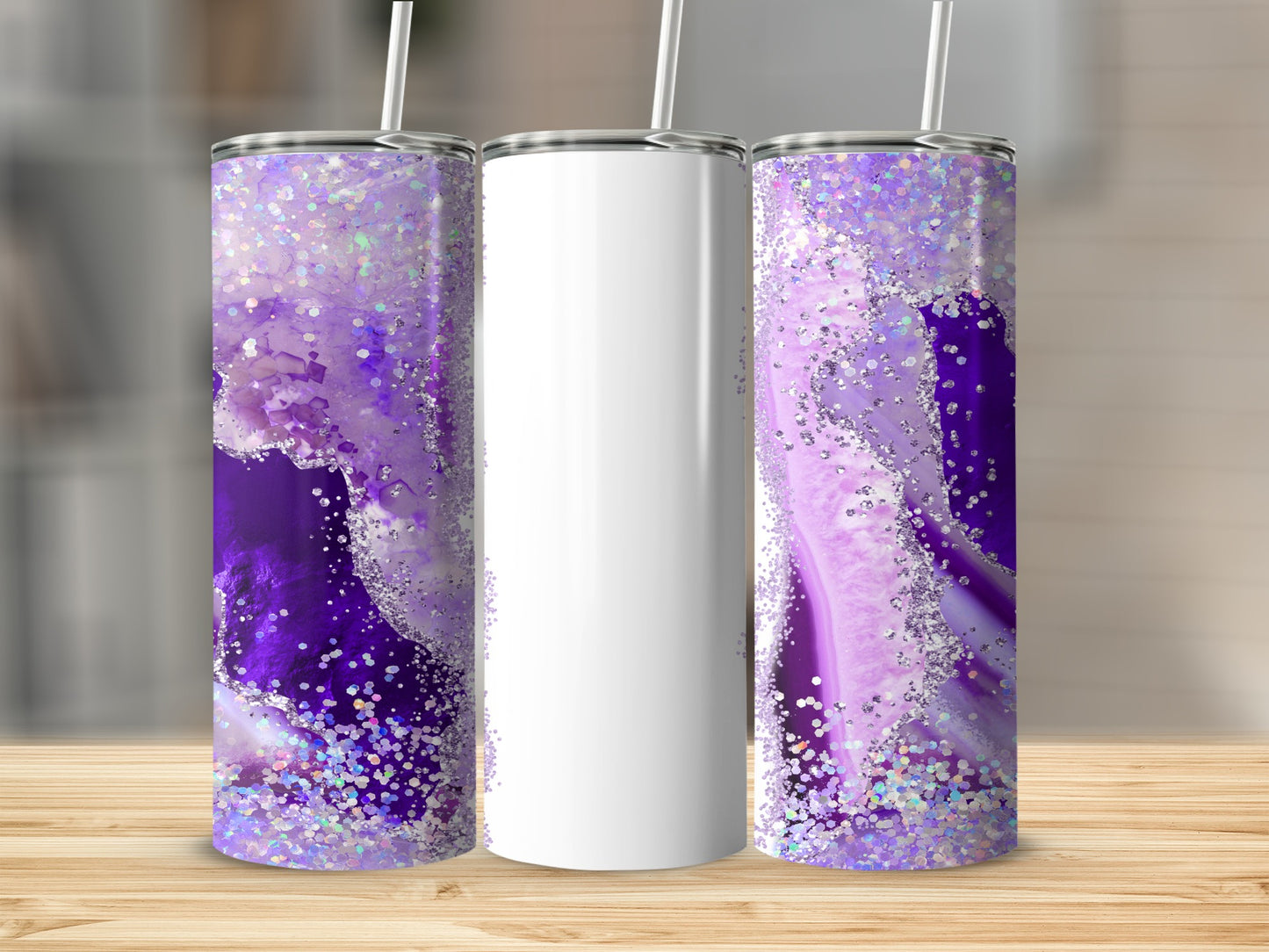 Three tumblers on a wooden surface, two with purple geode design and glitter.