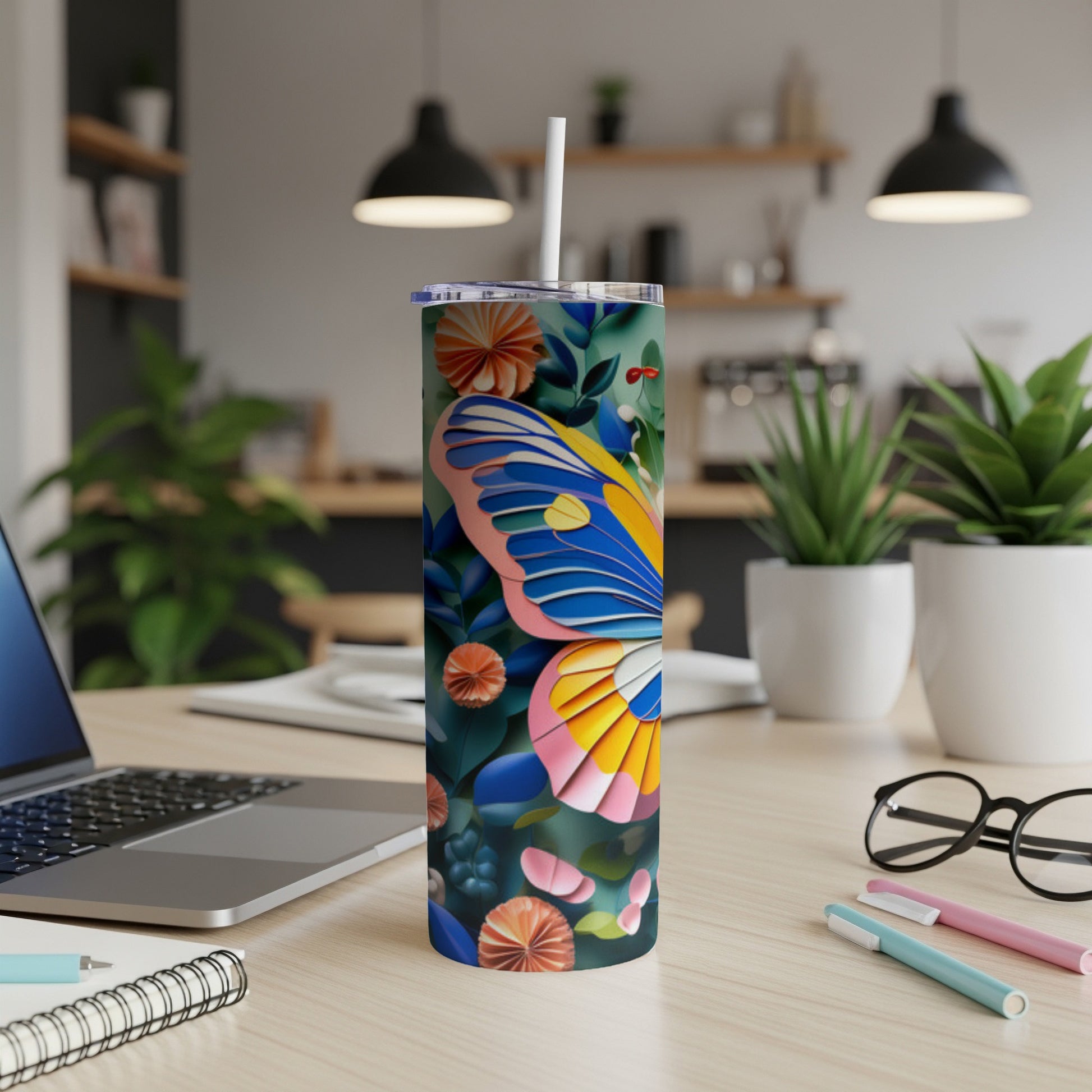Tumbler with colorful butterfly and floral pattern on a desk.