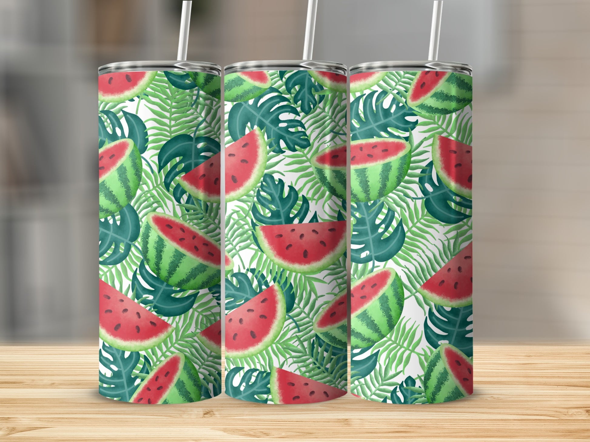 Three tumblers with a watermelon and palm leaf pattern on a wooden surface.