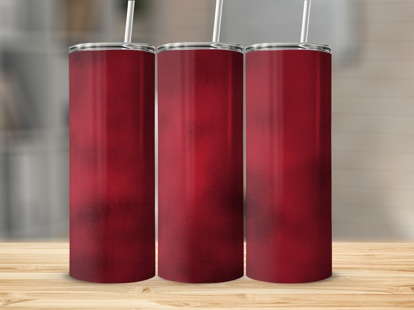 Three tall, narrow red tumblers with straws stand on a wooden surface.