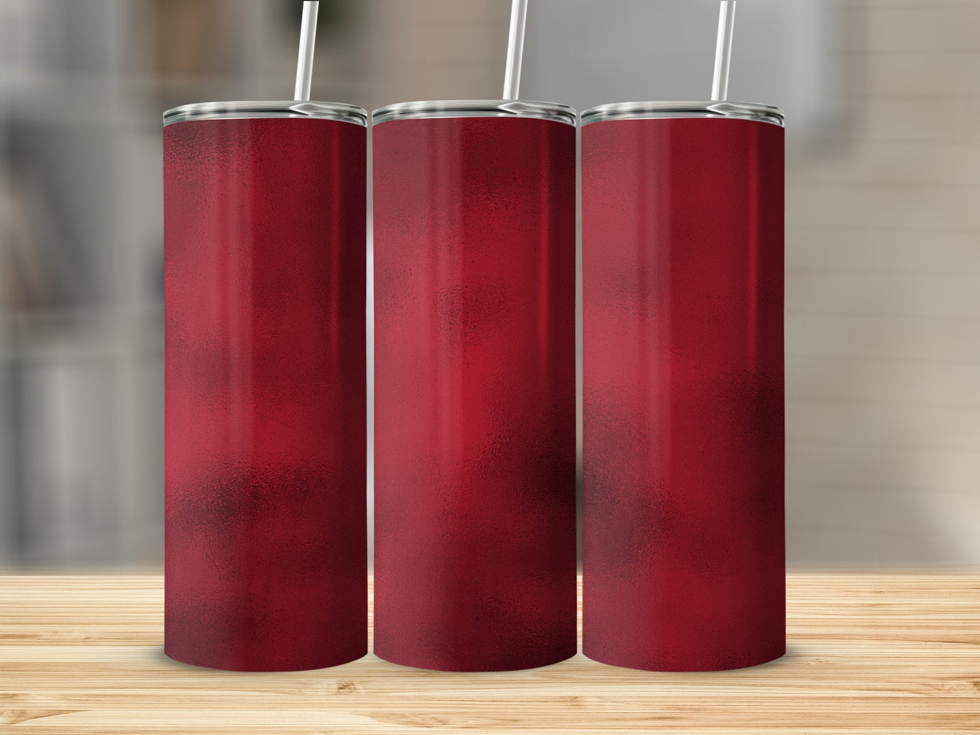 Three tall, narrow red tumblers with straws stand on a wooden surface.