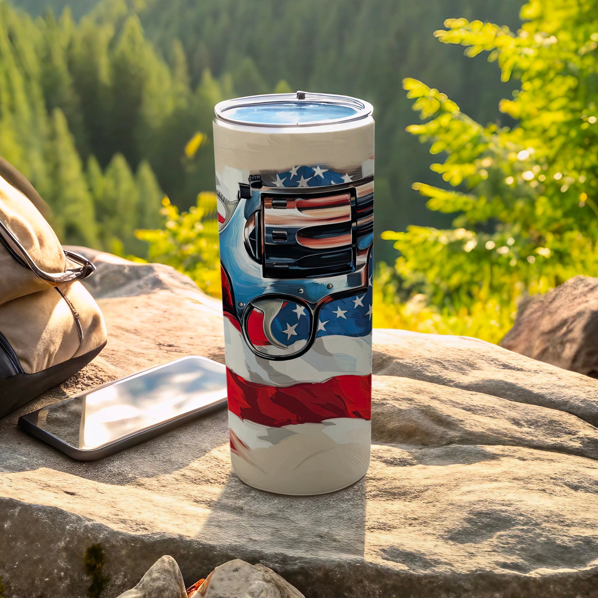 Tumbler with American flag and gun design, resting on rock.