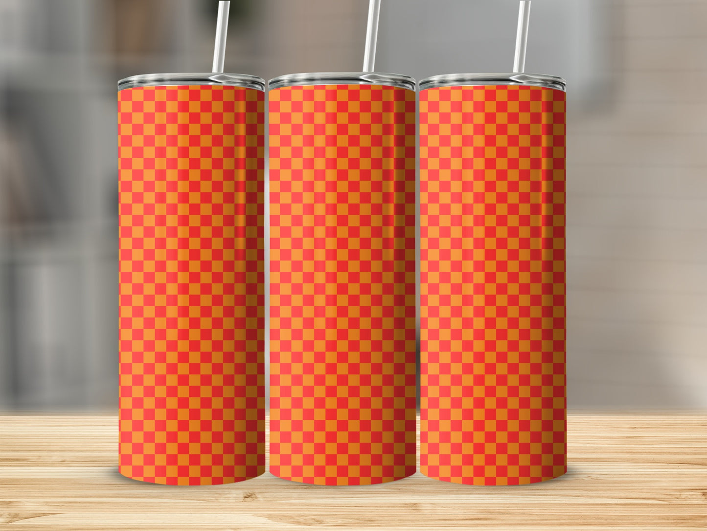 Three tall, orange and red checkered tumblers with straws stand on a wooden surface.