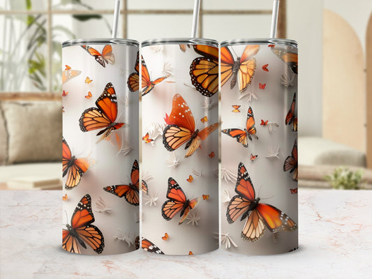 Three tumblers with orange monarch butterflies and floral accents.