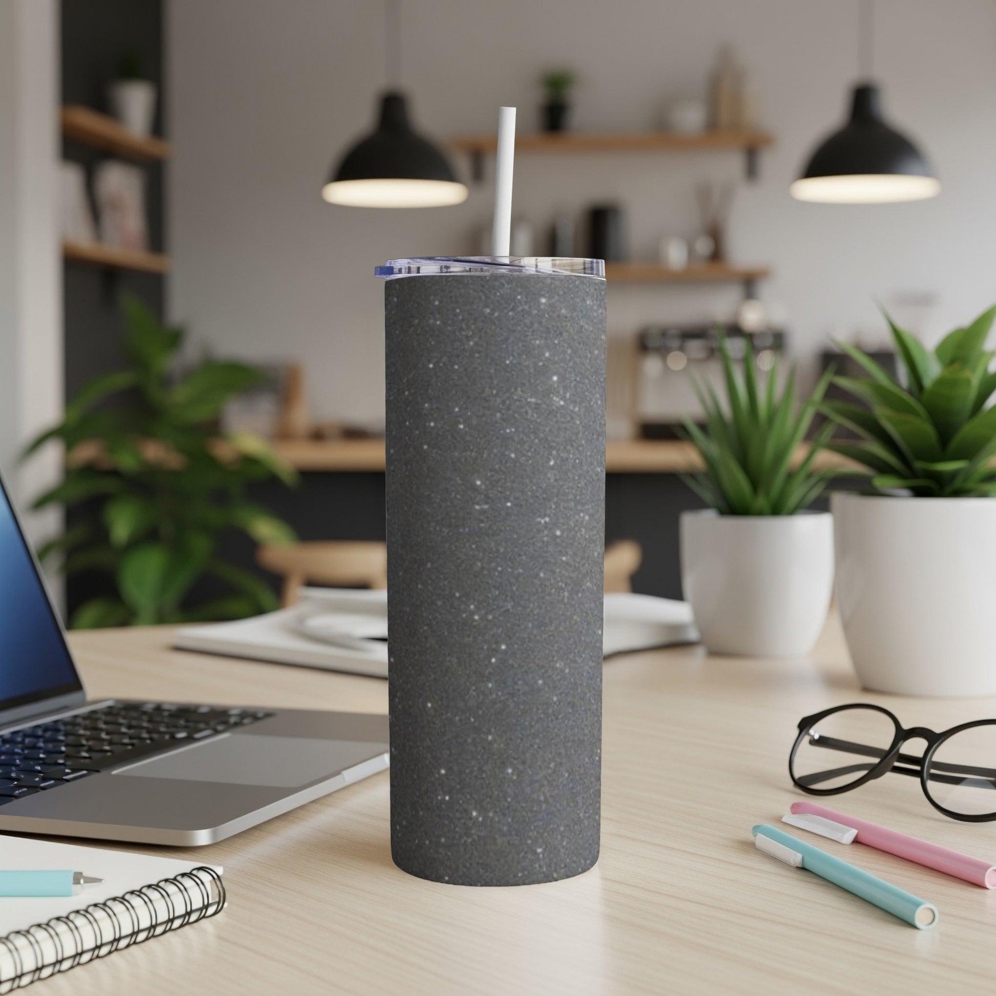 Dark gray speckled tumbler with white straw on a desk.
