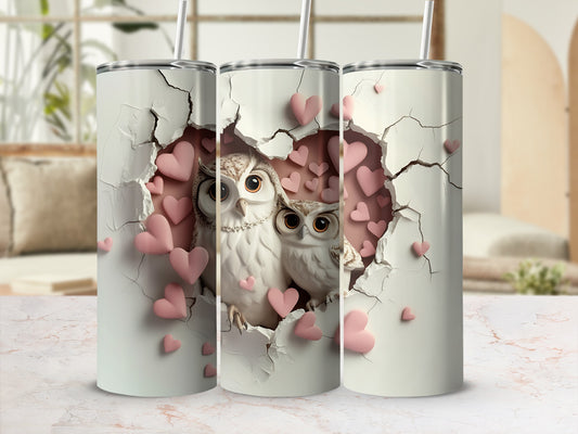 Two owls with pink hearts on a cracked white tumbler.