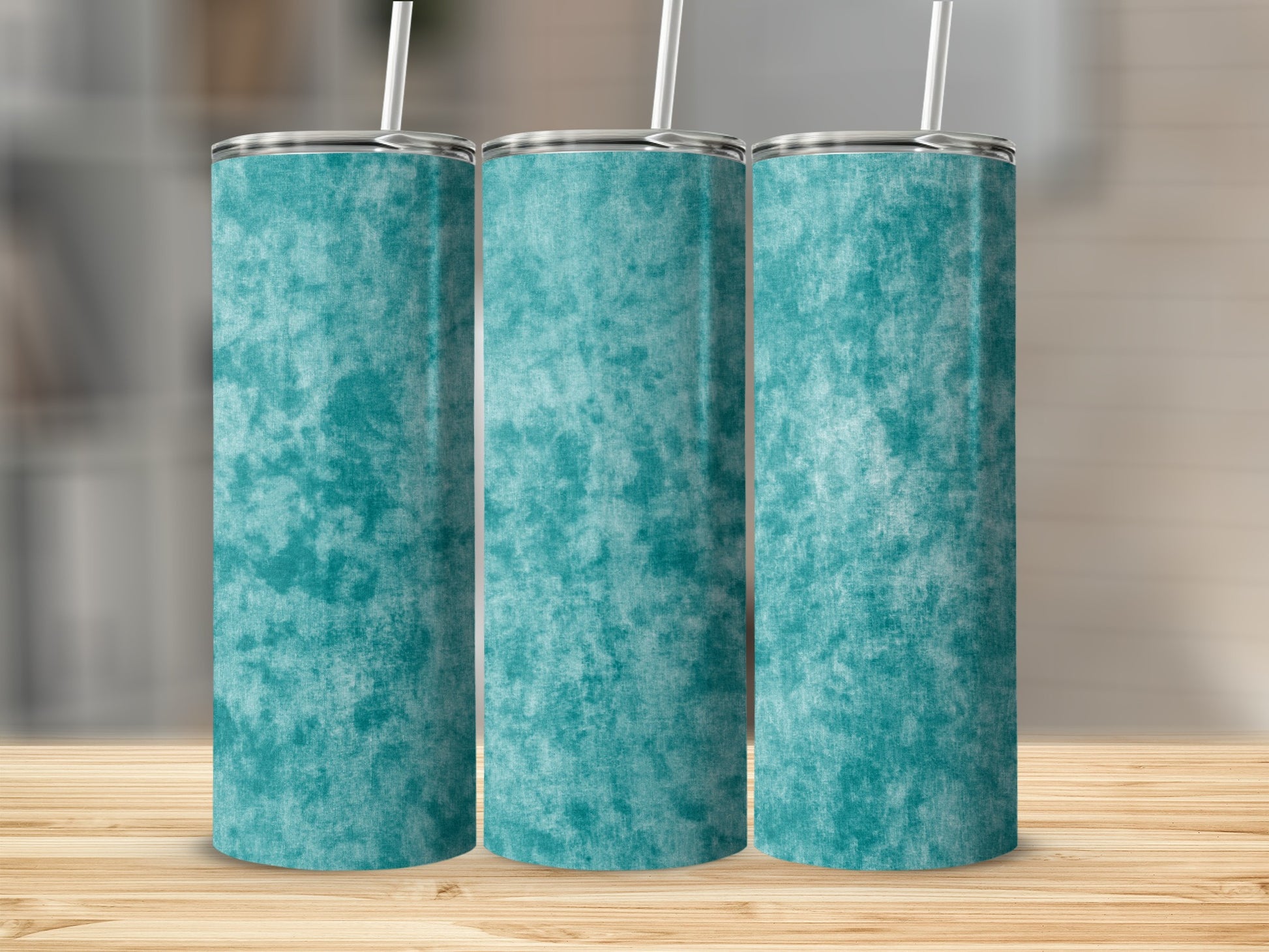Three teal marbled tumblers with straws on a wooden surface.