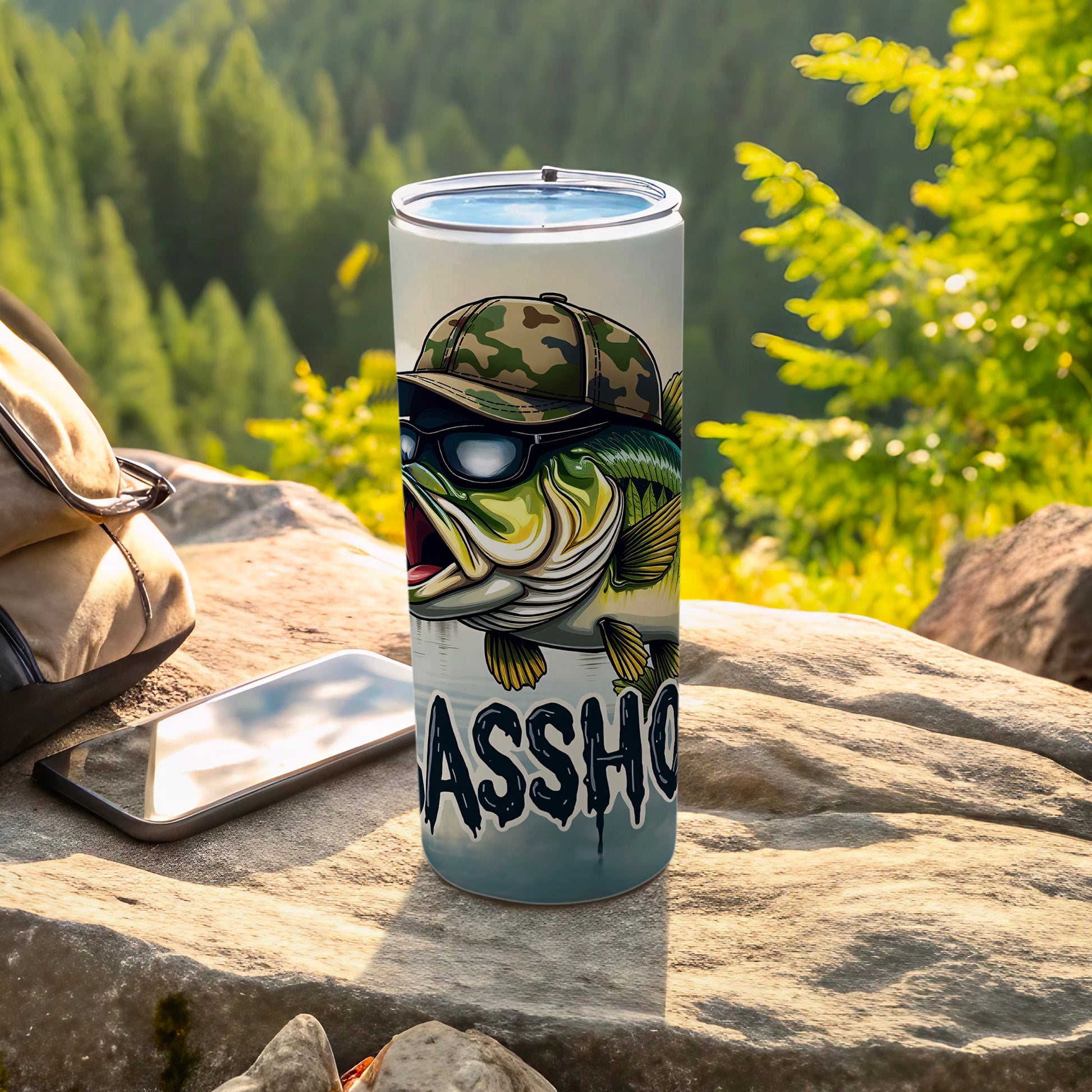 Bass fishing tumbler with sunglasses and camouflage hat, resting outdoors.