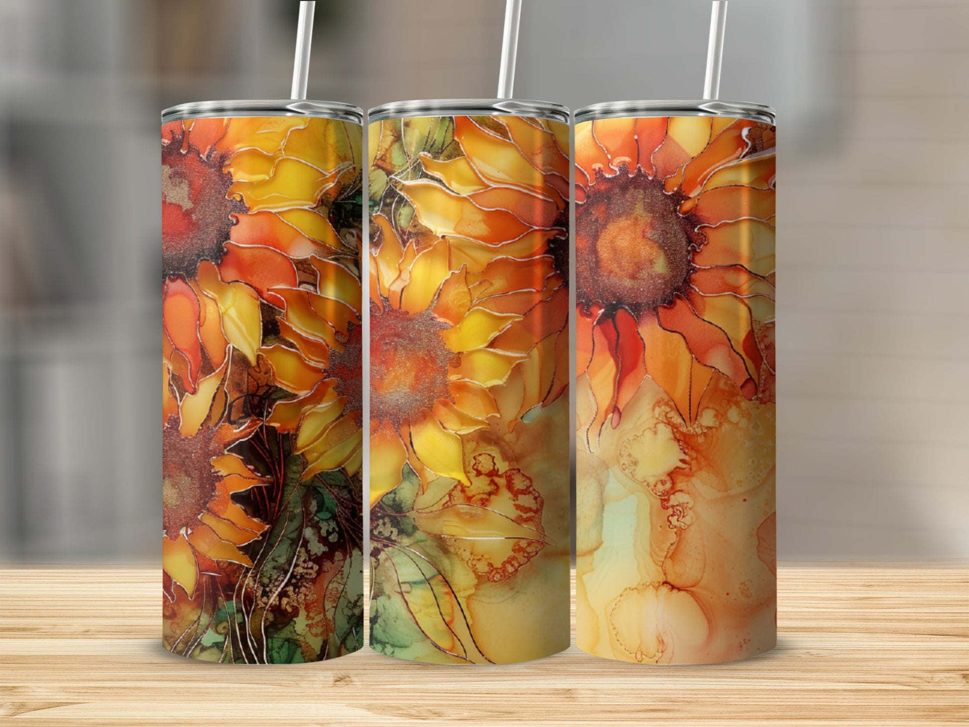 Three tumblers with a vibrant sunflower pattern on a wooden surface.