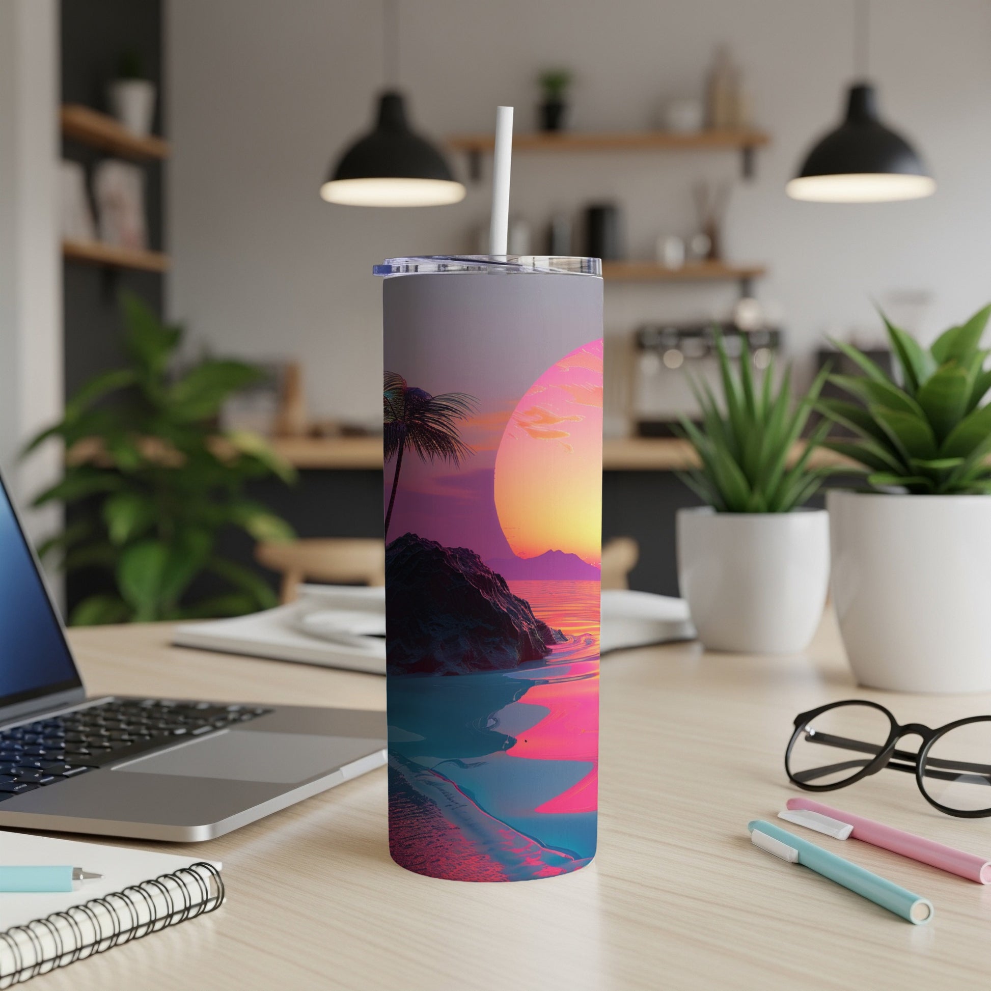 Sunset beach scene on a tumbler with a straw, displayed on a desk.