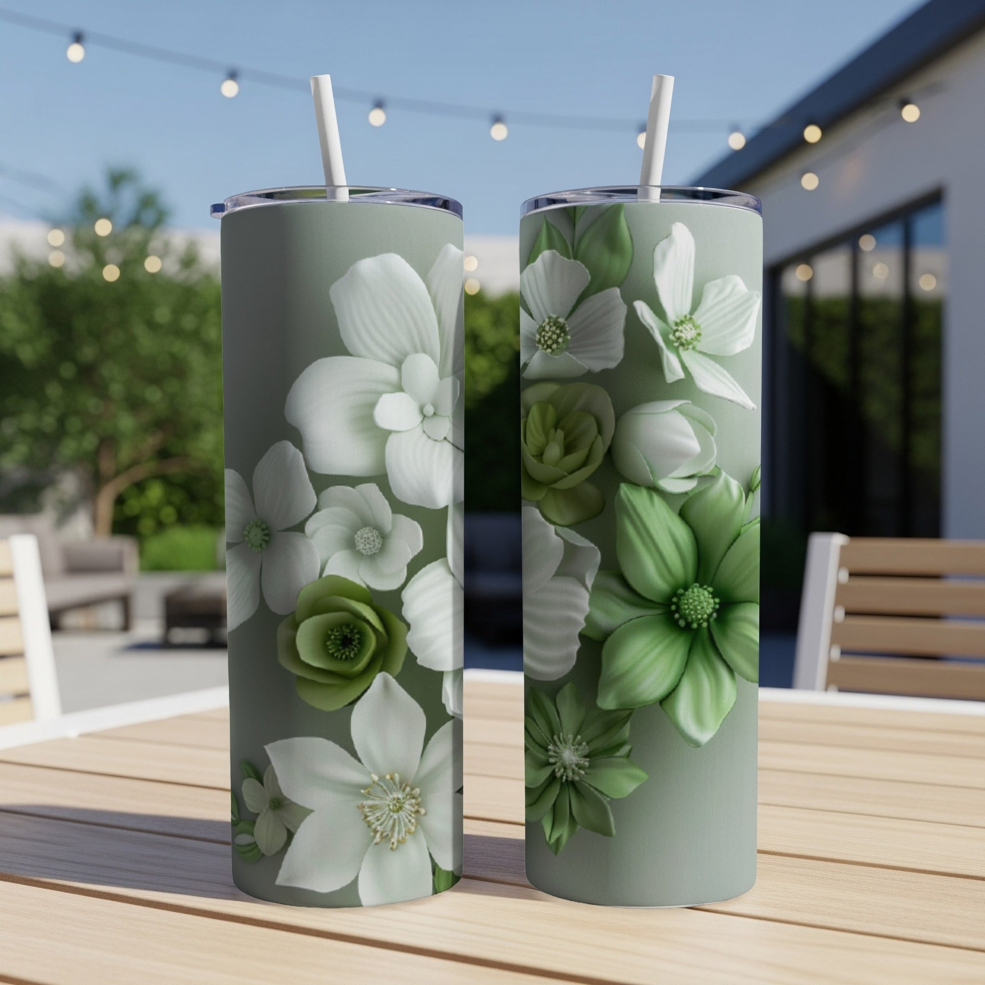 Two green tumblers with floral designs sit on a wooden table outdoors.