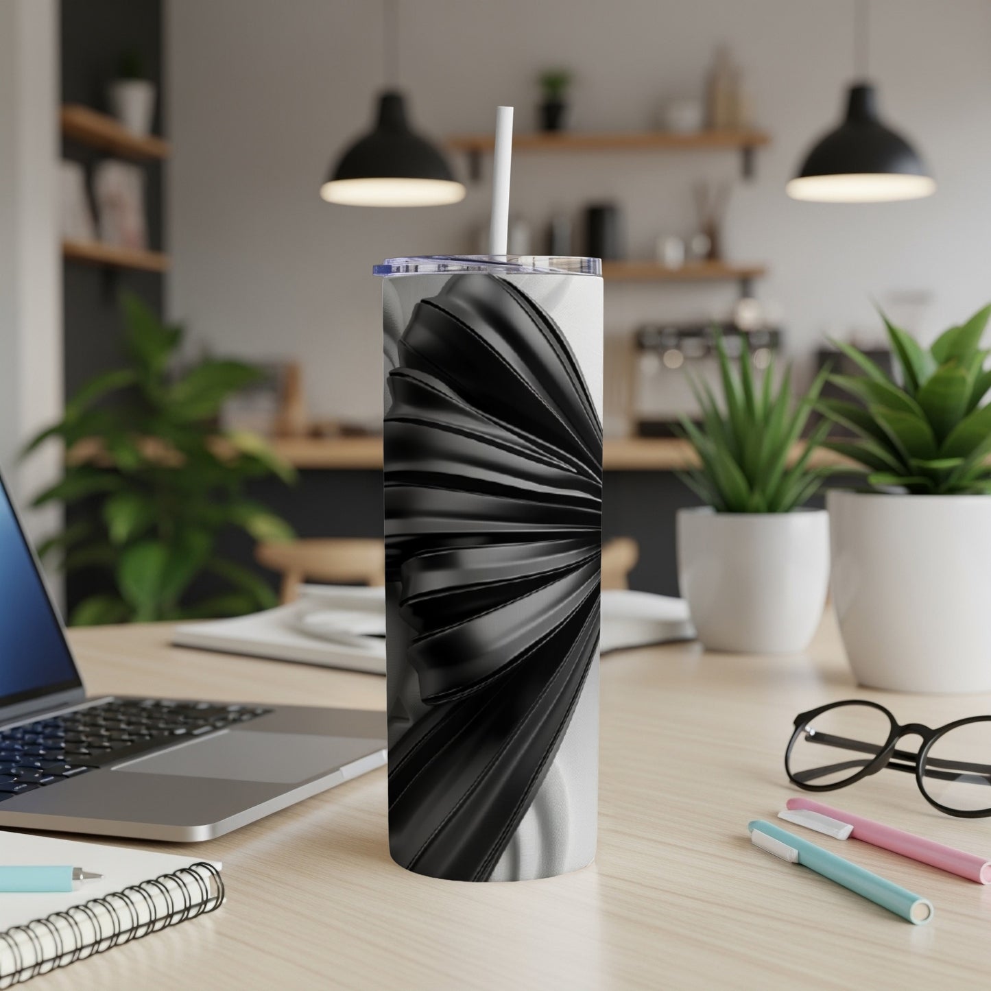Black and white ribbed tumbler with straw on a desk.