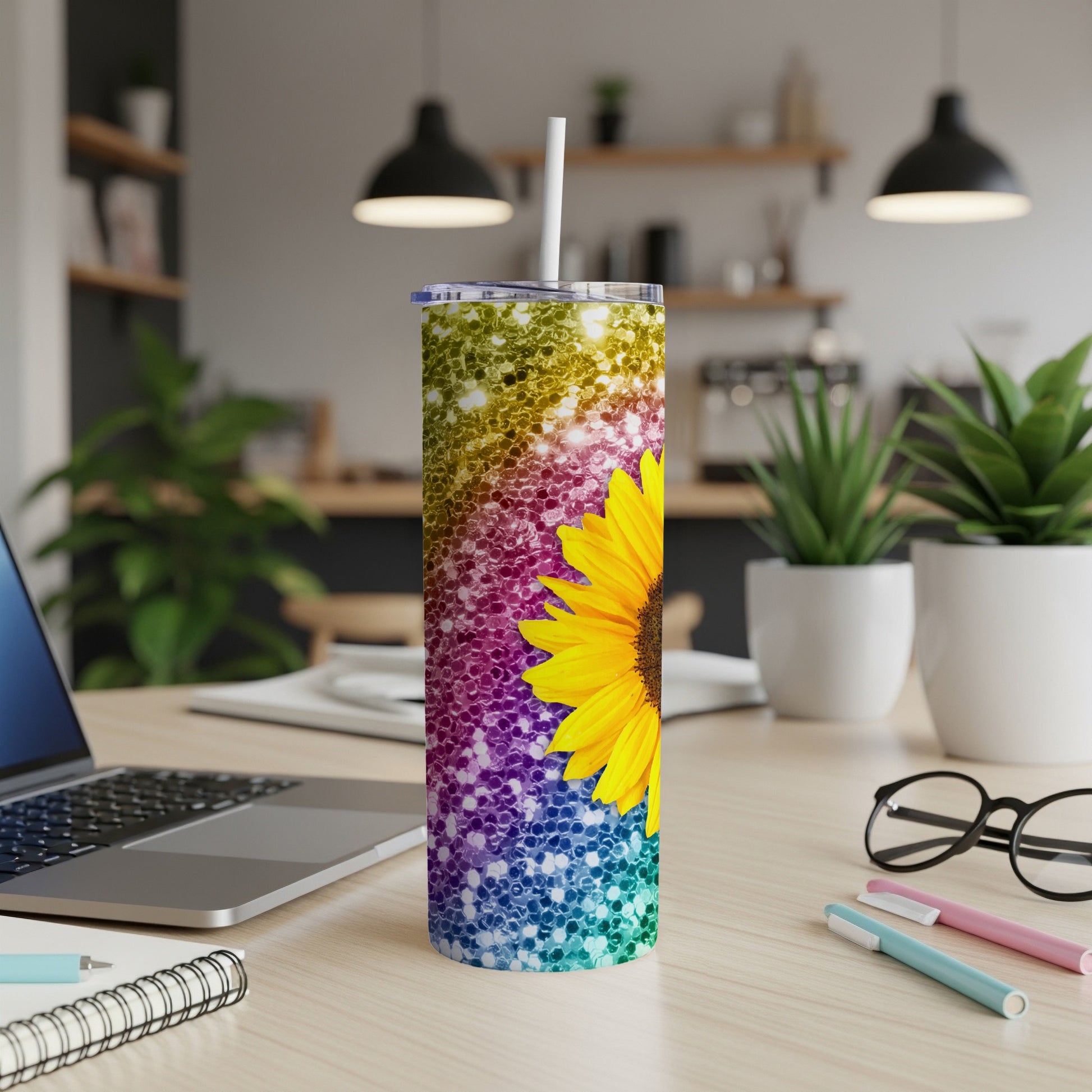 Glittery sunflower tumbler with a white straw on a desk.