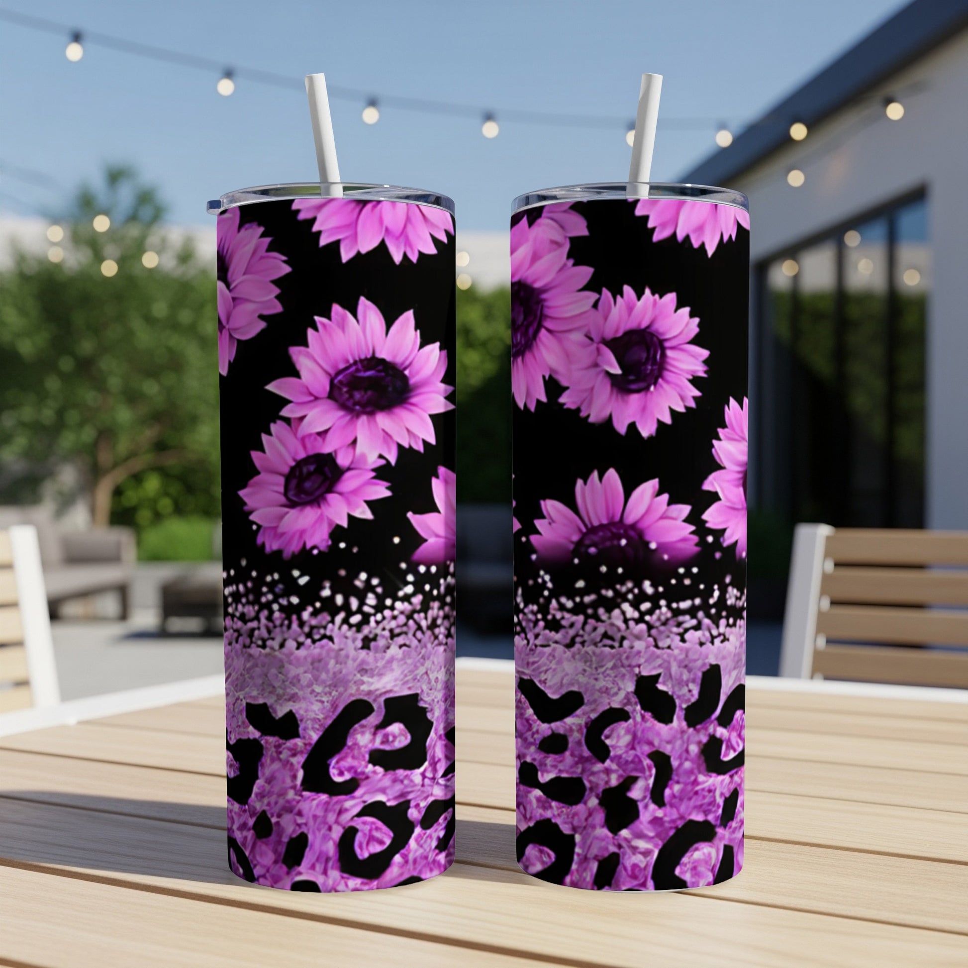 Two pink sunflowers and purple leopard print tumblers on a wooden table.