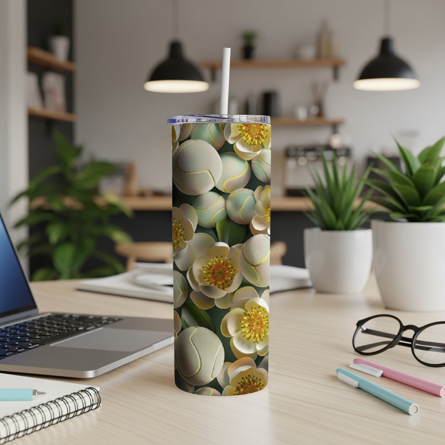 White and yellow floral pattern on a white tumbler with a straw, on a desk.