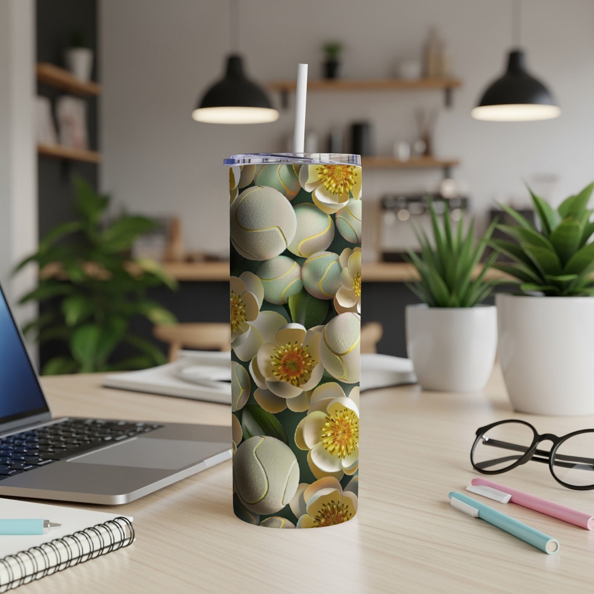 White and yellow floral pattern on a white tumbler with a straw, on a desk.