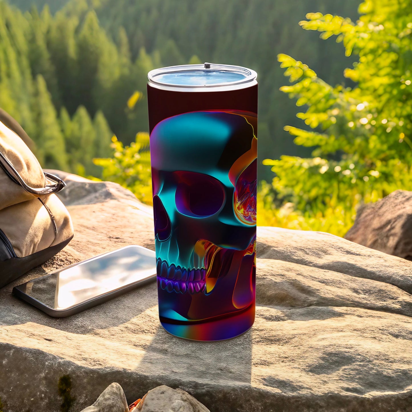 Tumbler with colorful neon skull design sits on rocks near backpack.