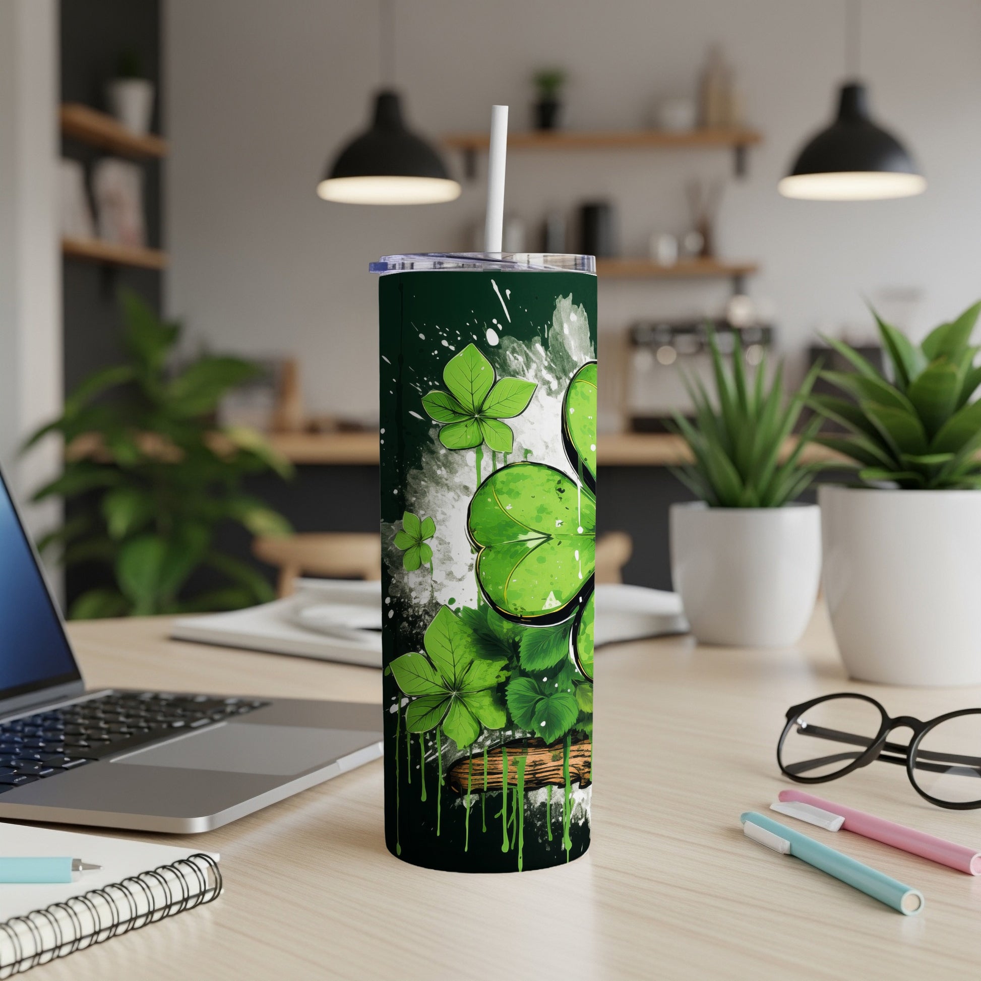 Green tumbler with shamrocks and dripping paint on a desk.