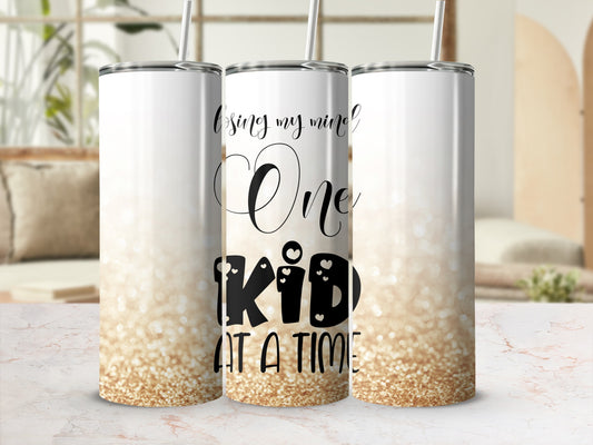 White tumbler with "Losing My Mind One Kid At A Time" text and glitter gradient.