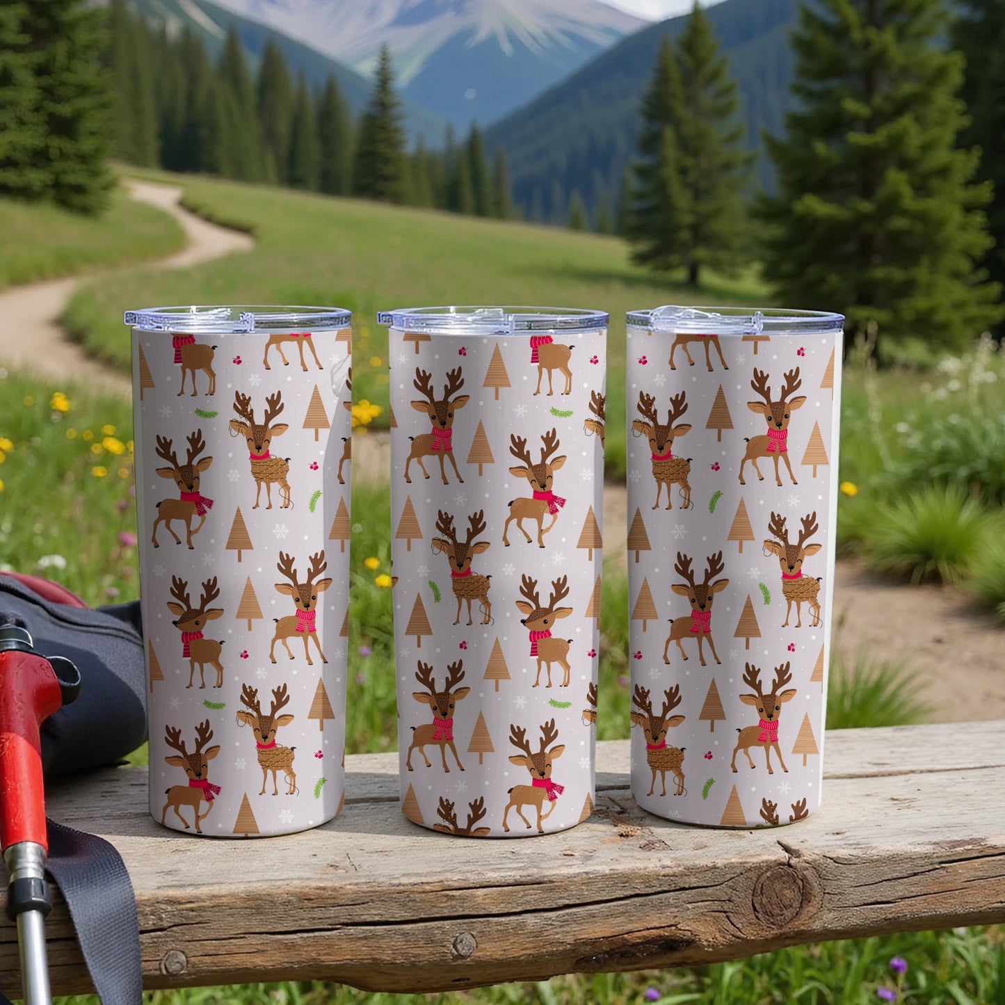 Three tumblers with a reindeer and snowflake pattern on a wooden surface.
