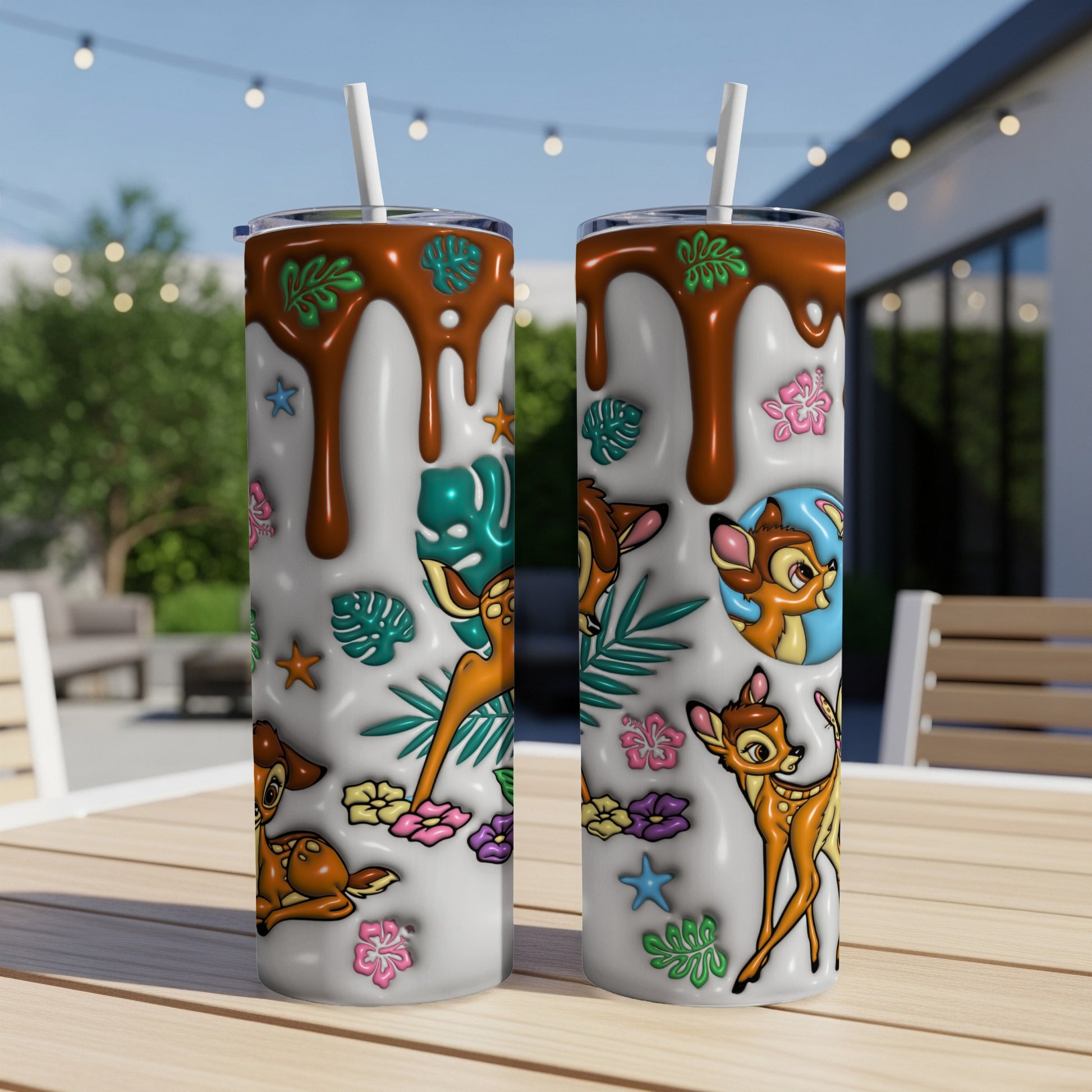 Two tumblers with Bambi characters and tropical leaves on a patio table.