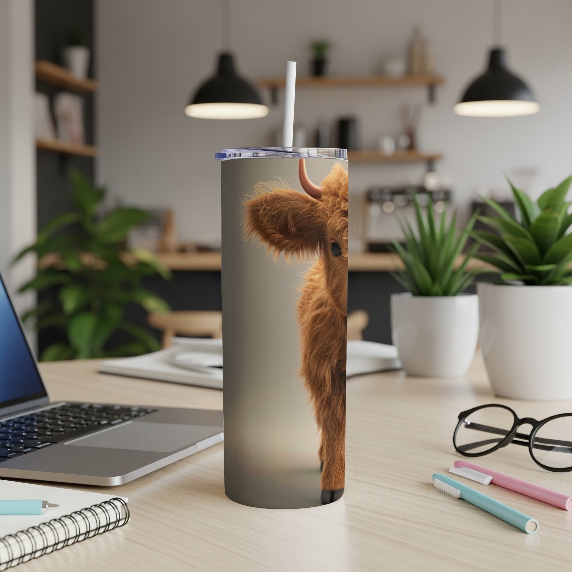 Close up of a fluffy Highland cow peeking around a stainless steel tumbler.