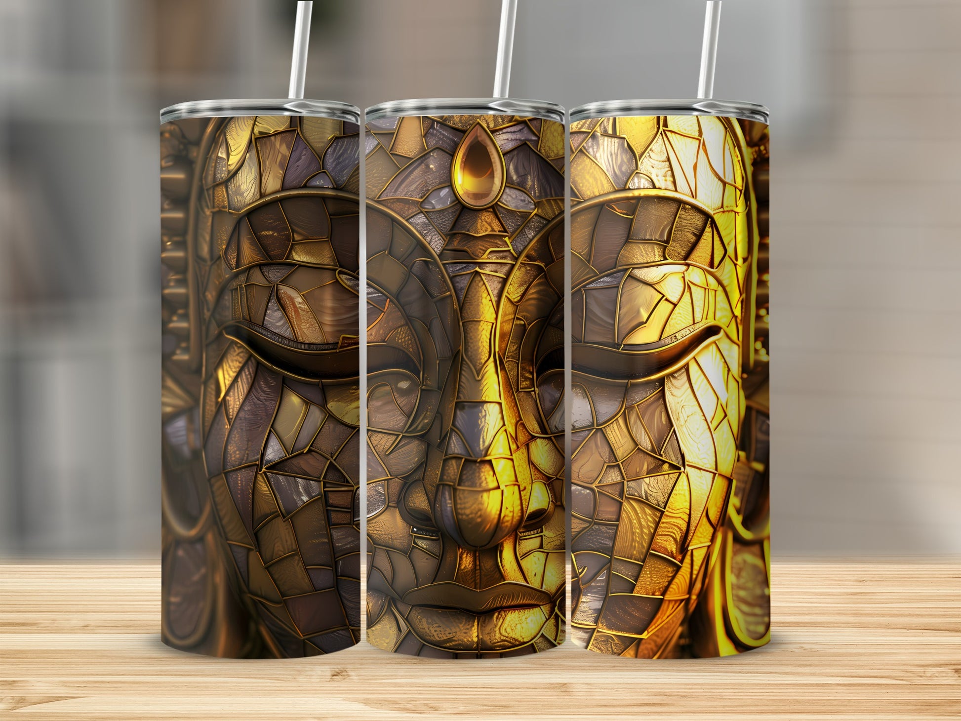 Three tumblers with intricate golden Buddha face design on a wooden surface.