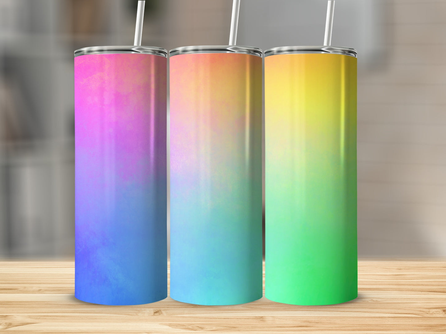 Three tall tumblers with gradient colors on a wooden surface.