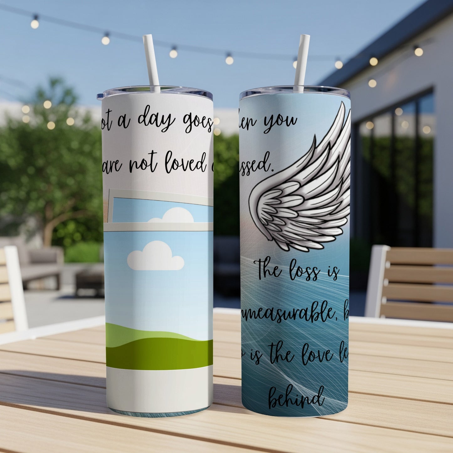 Two tumblers with quotes and an angel wing design on a table.