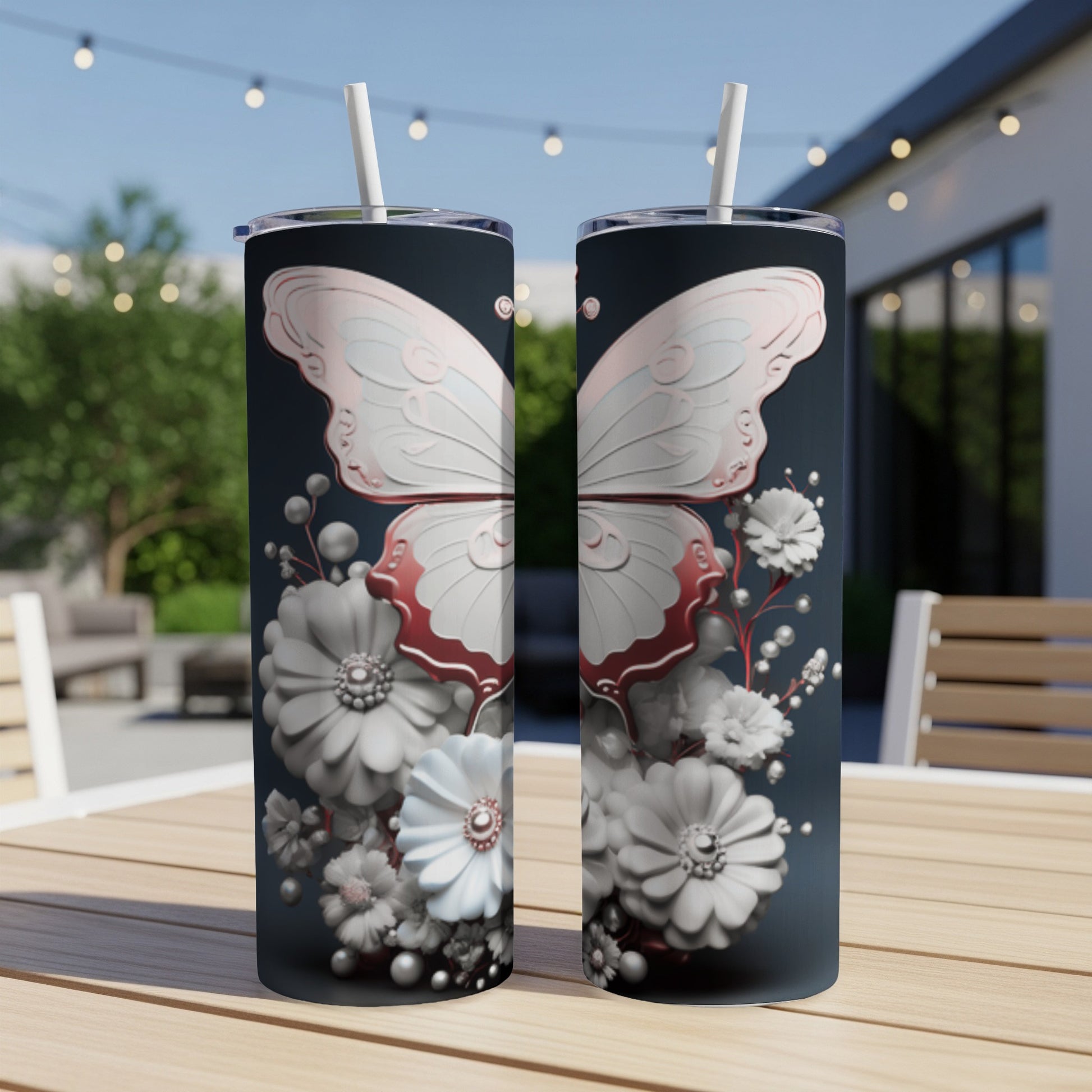 Two tumblers with a butterfly and floral design sit on a wooden table outdoors.
