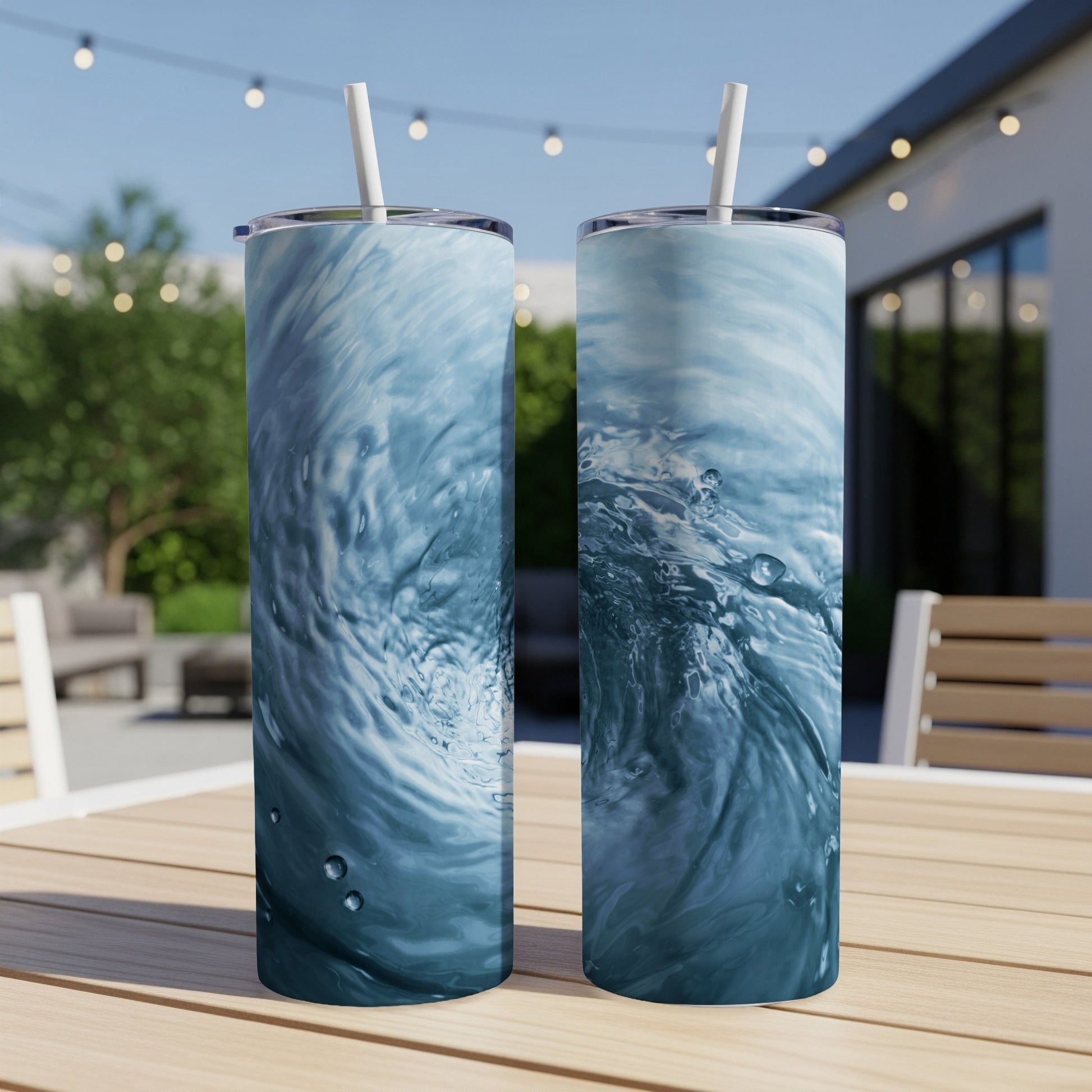 Two tall tumblers with swirling blue water patterns sit on a patio table.