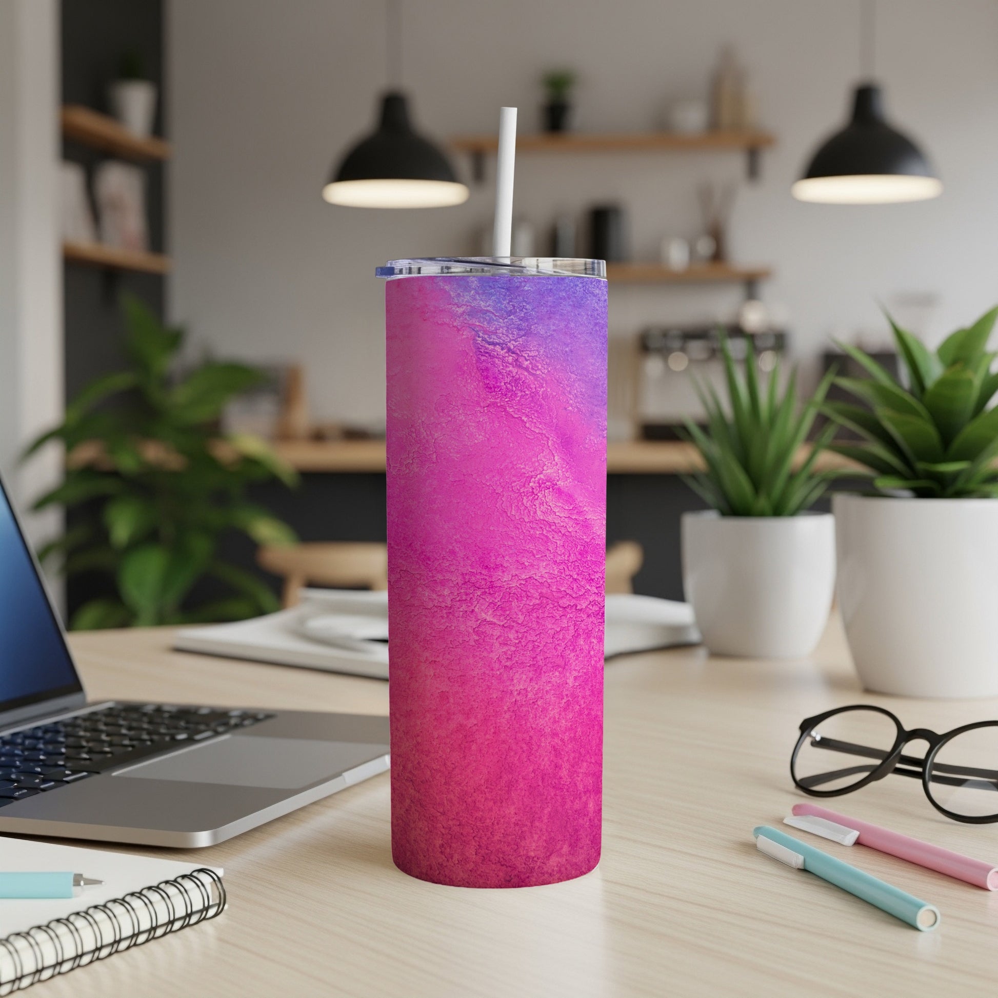 Pink and purple abstract pattern tumbler with straw on a desk.