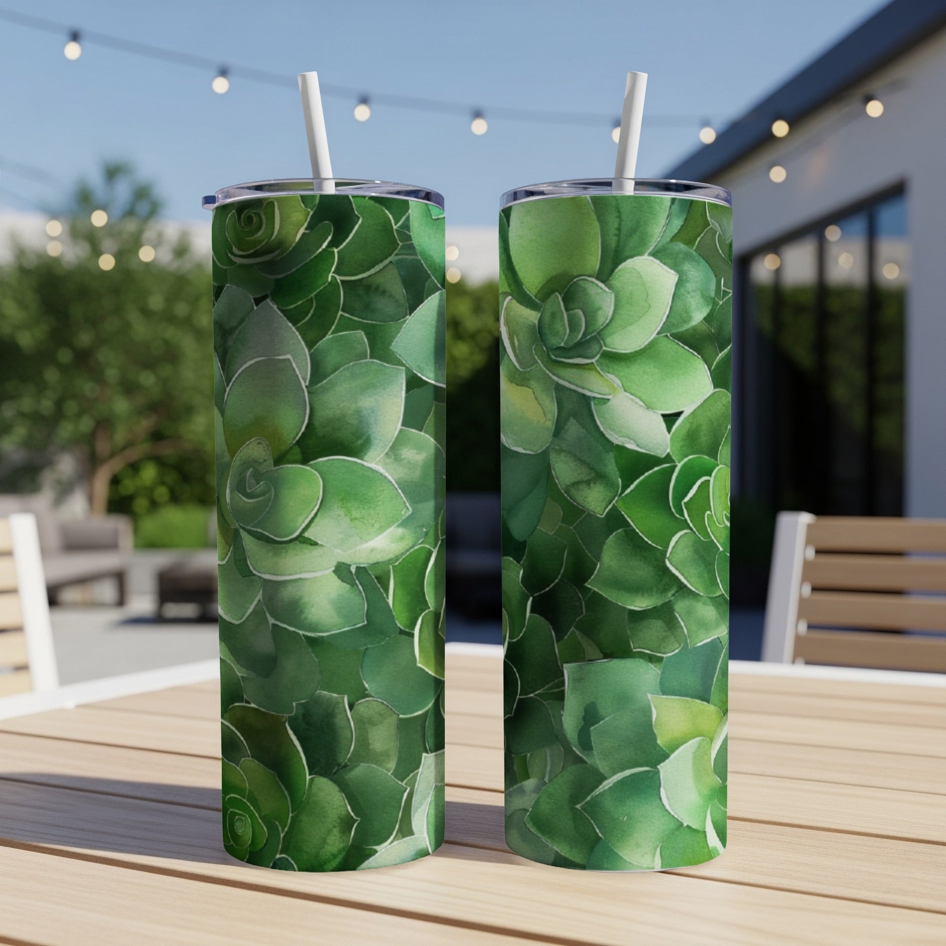 Two tumblers with a green succulent pattern sit on a wooden table outdoors.