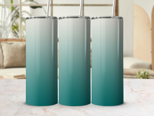 Three tumblers with a teal and white gradient design, standing on a marble countertop.