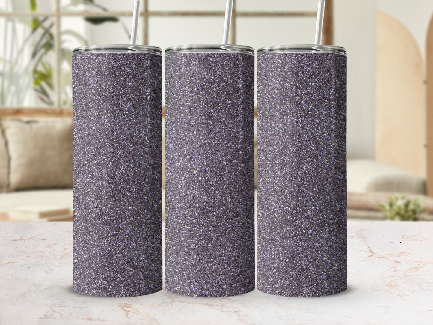 Three glitter tumblers with straws on a marble surface.