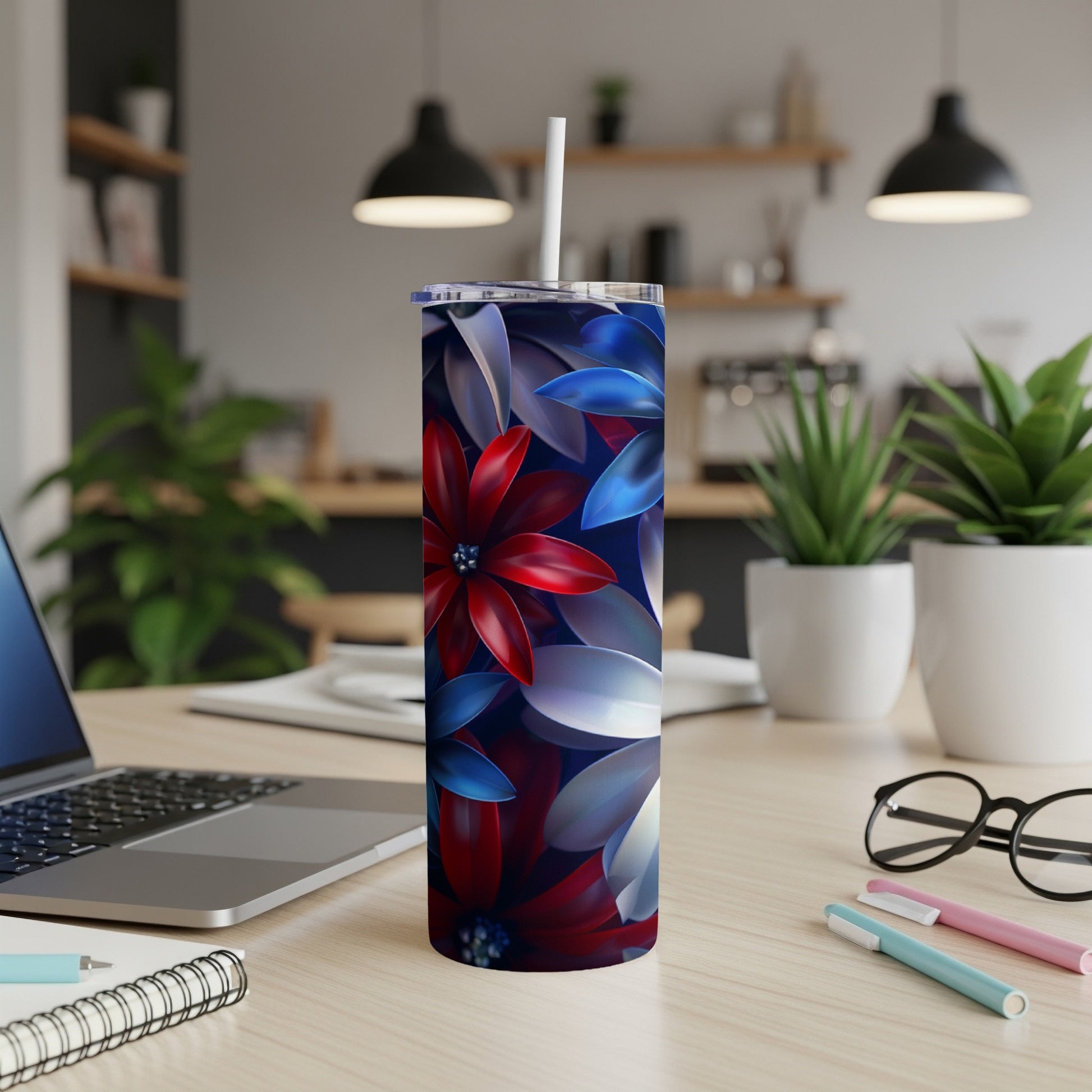 Red, white, and blue floral tumbler with straw on a desk.
