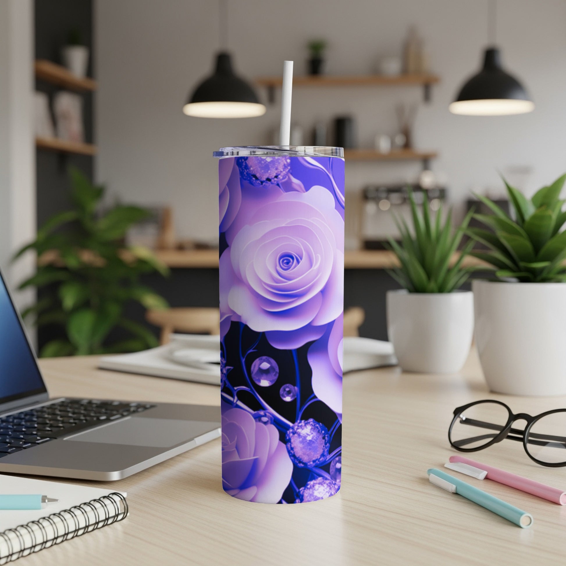 Purple rose pattern on a tall tumbler with a straw, on a desk.