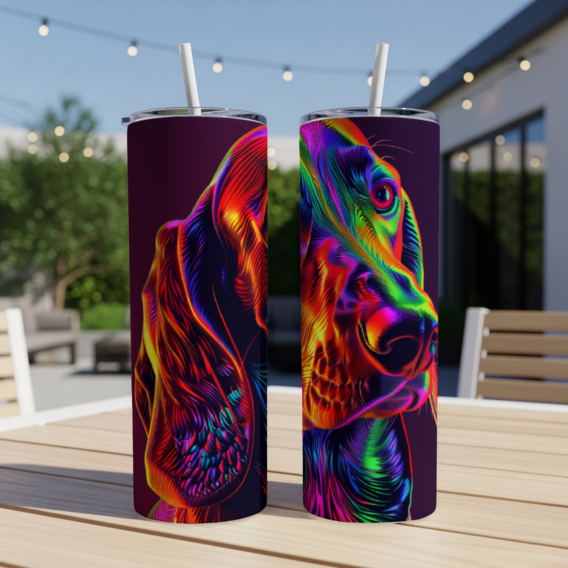 Two tumblers with colorful, abstract dog portraits on a table outdoors.