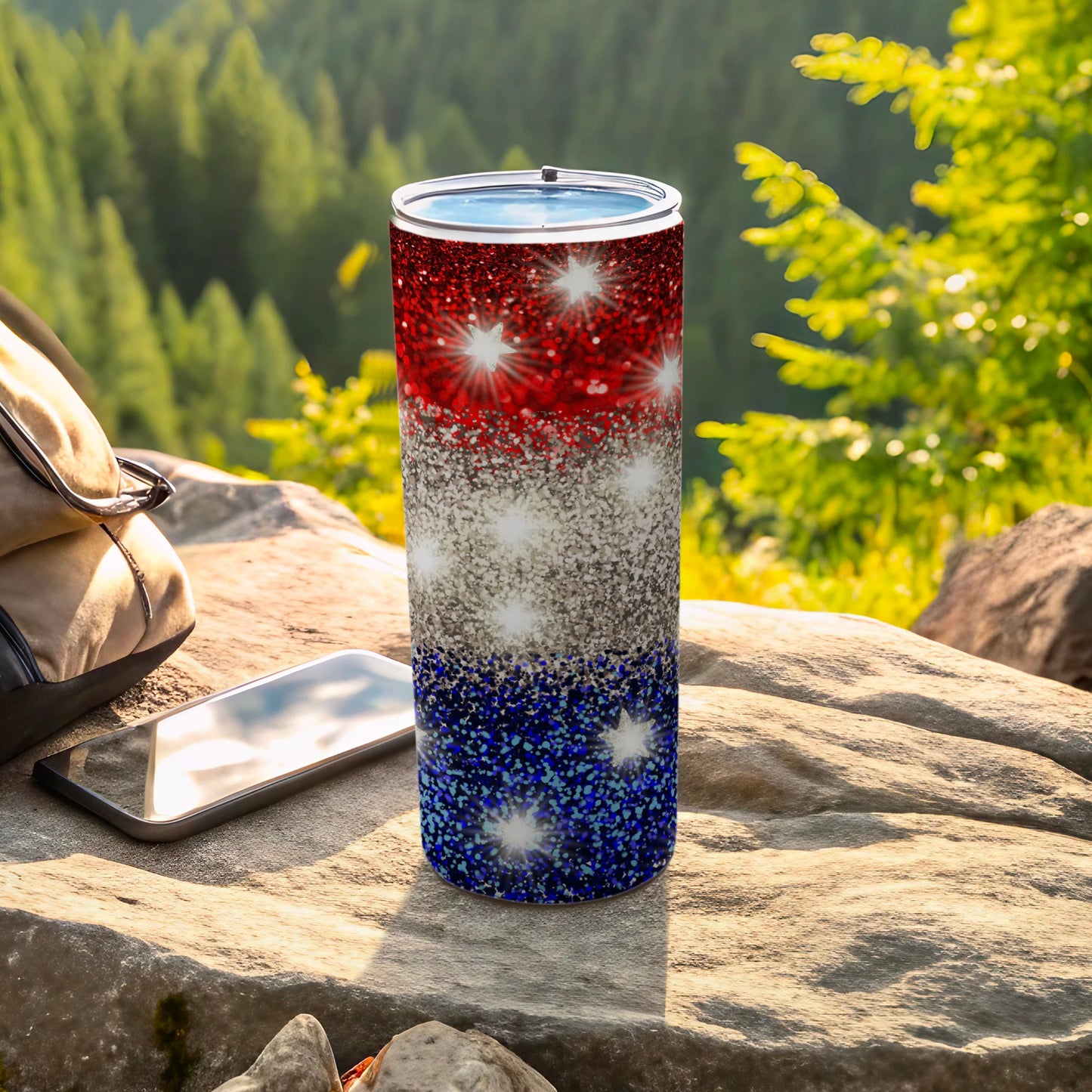 Glittering red, white, and blue patriotic tumbler on rocky surface.