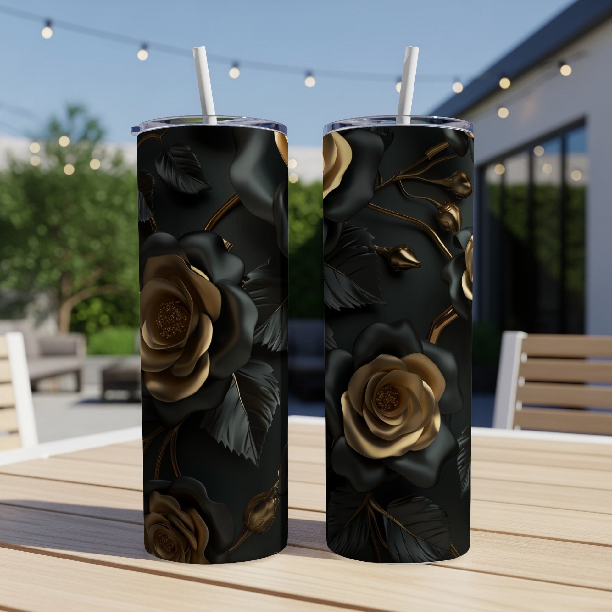 Two black tumblers with a raised gold rose and leaf design on a table.