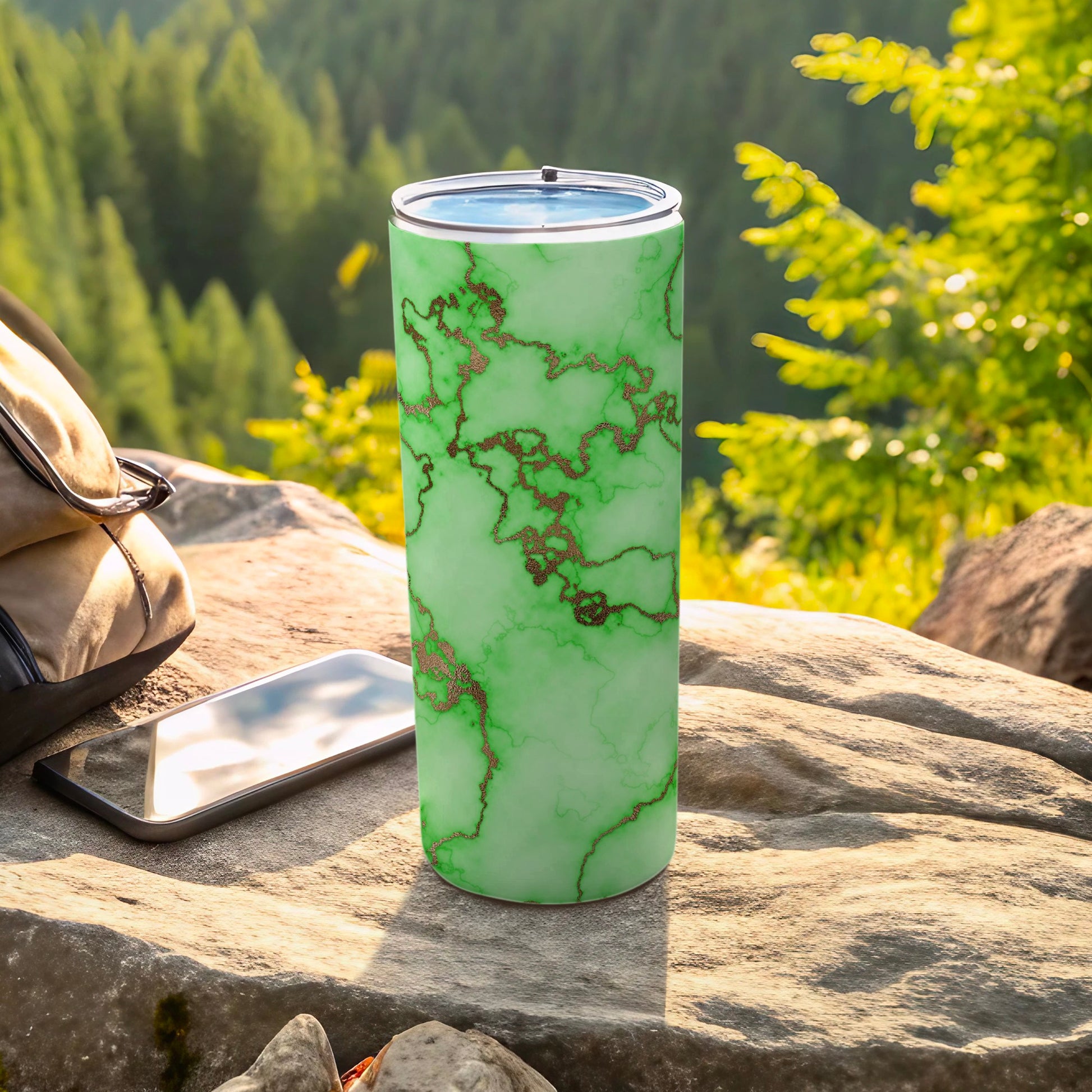 Green marble patterned tumbler with copper accents outdoors on rocks.
