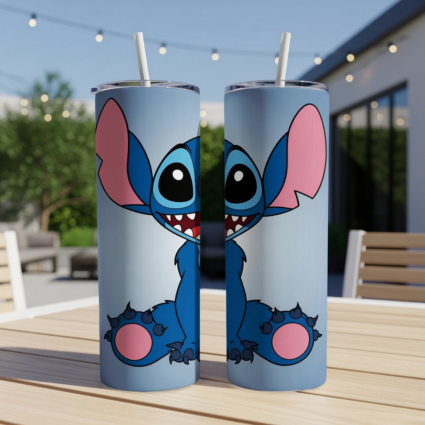 Two identical blue Stitch tumblers with straws on a wooden table outdoors.