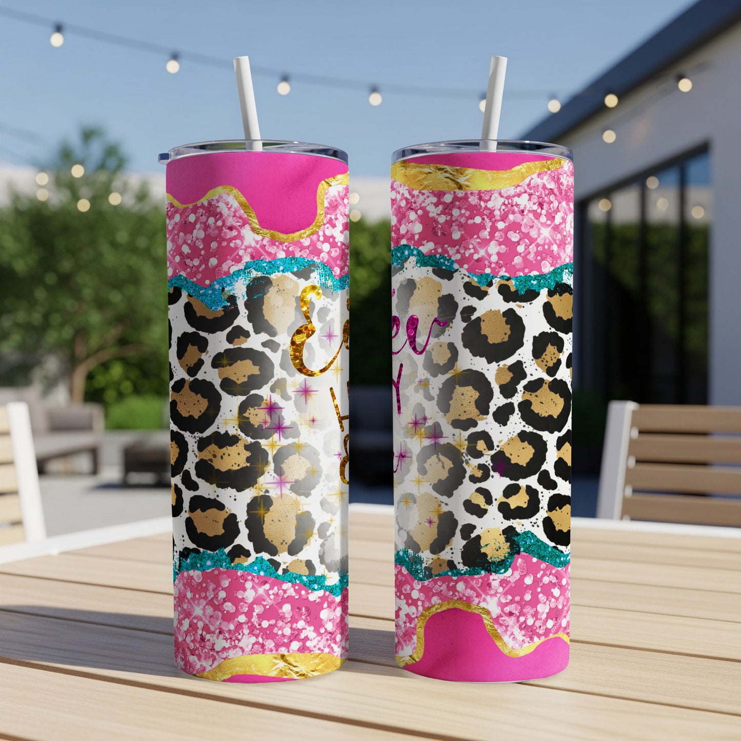 Two pink tumblers with leopard print and glitter designs on a wooden table.
