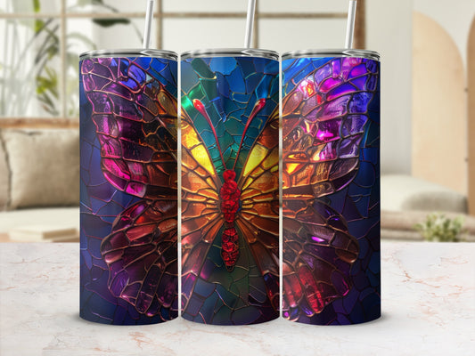 Stained glass butterfly tumbler with straw on marble surface.