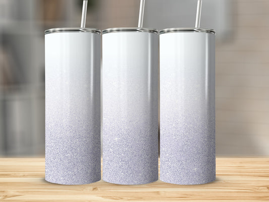 Three glitter gradient tumblers with straws stand on a wooden surface.
