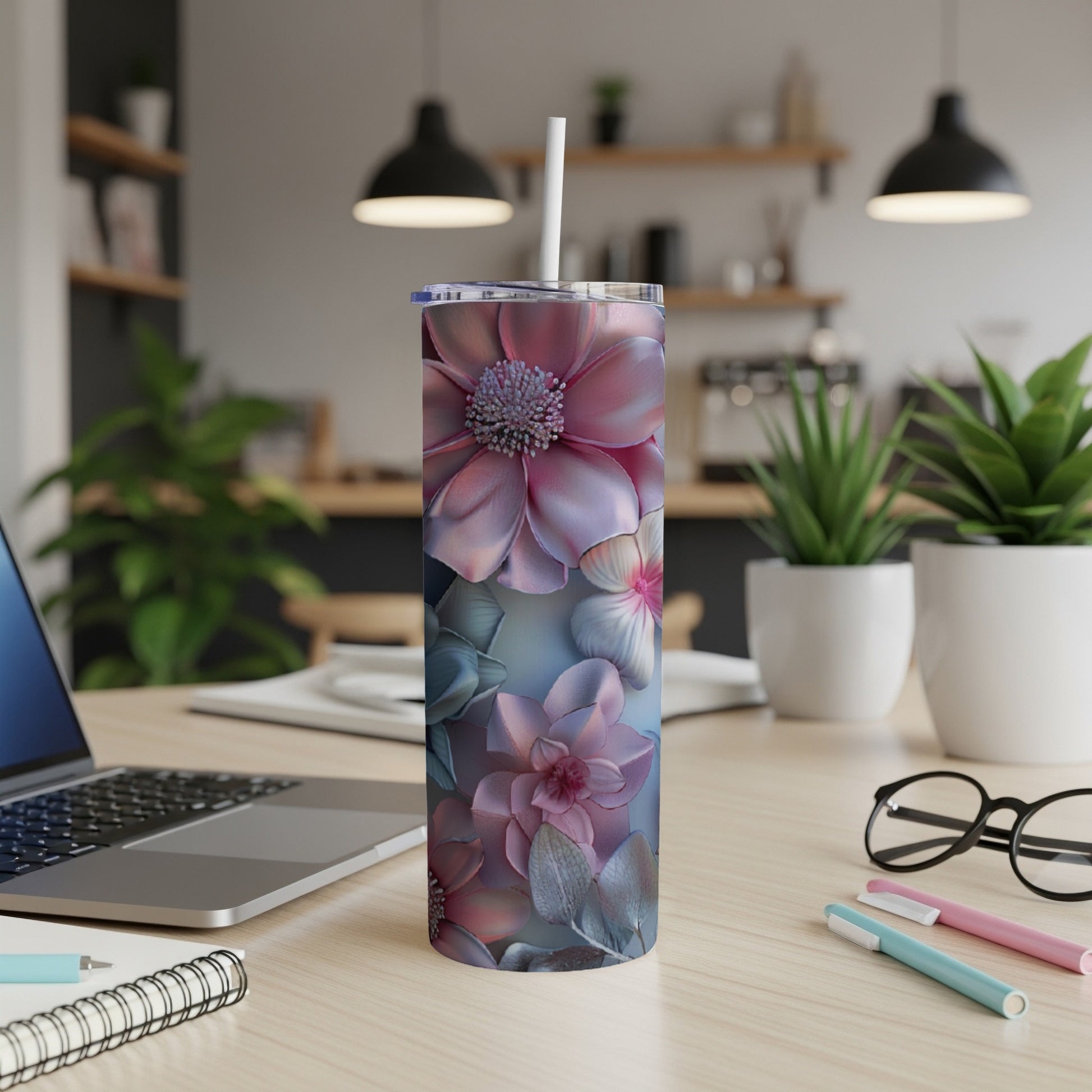 Pink and blue floral tumbler on a desk with a laptop and pens.