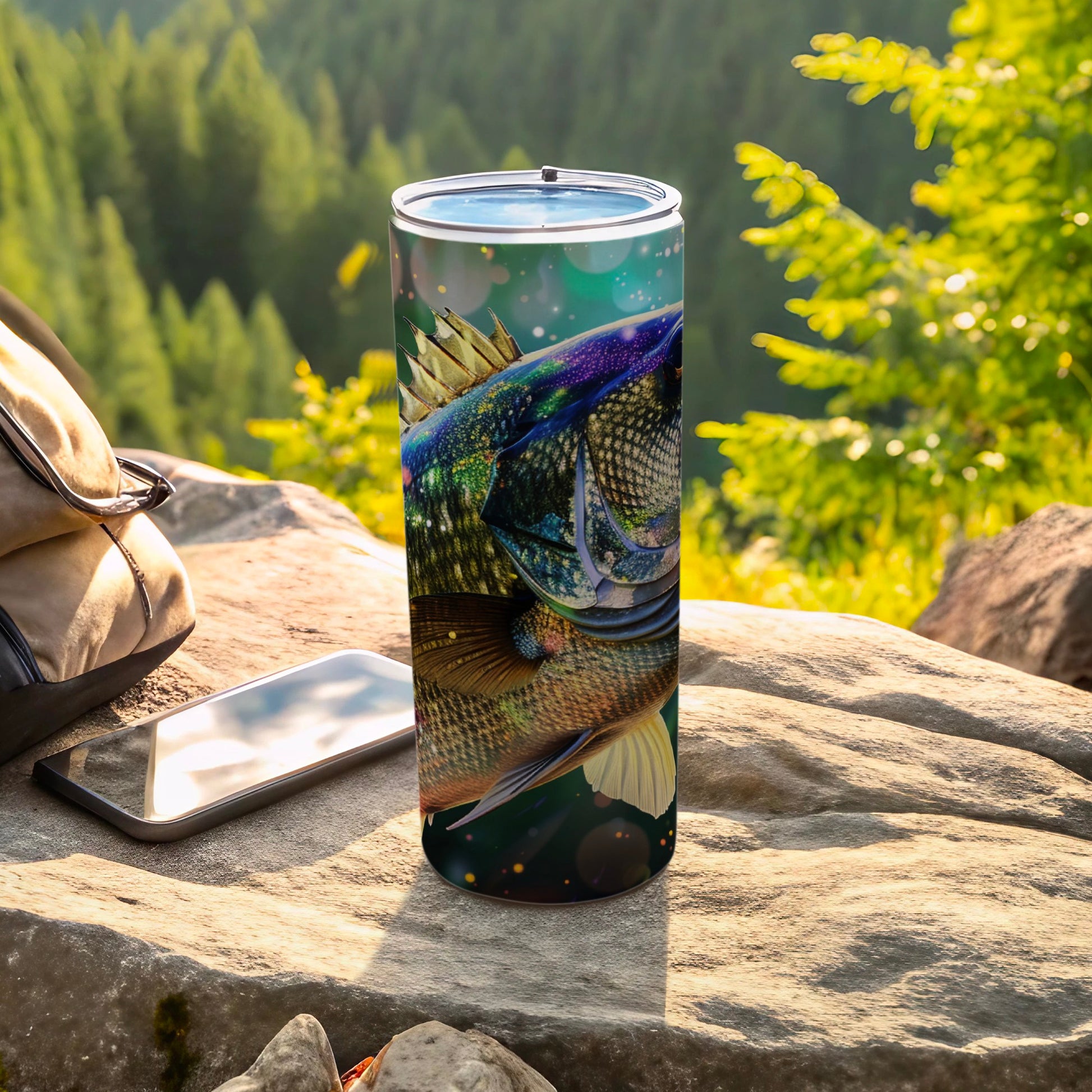 Tumbler with a vibrant fish illustration, set outdoors on rocks.