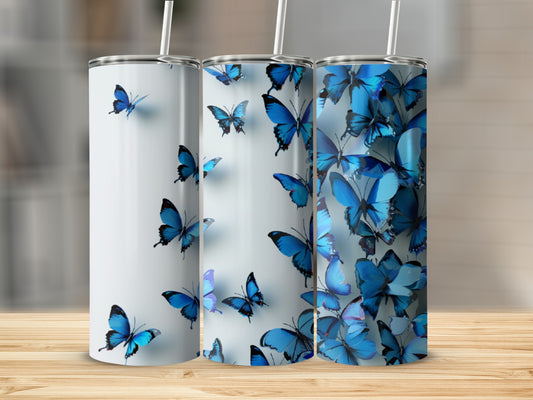 Three tumblers with blue butterfly designs on a wooden surface.