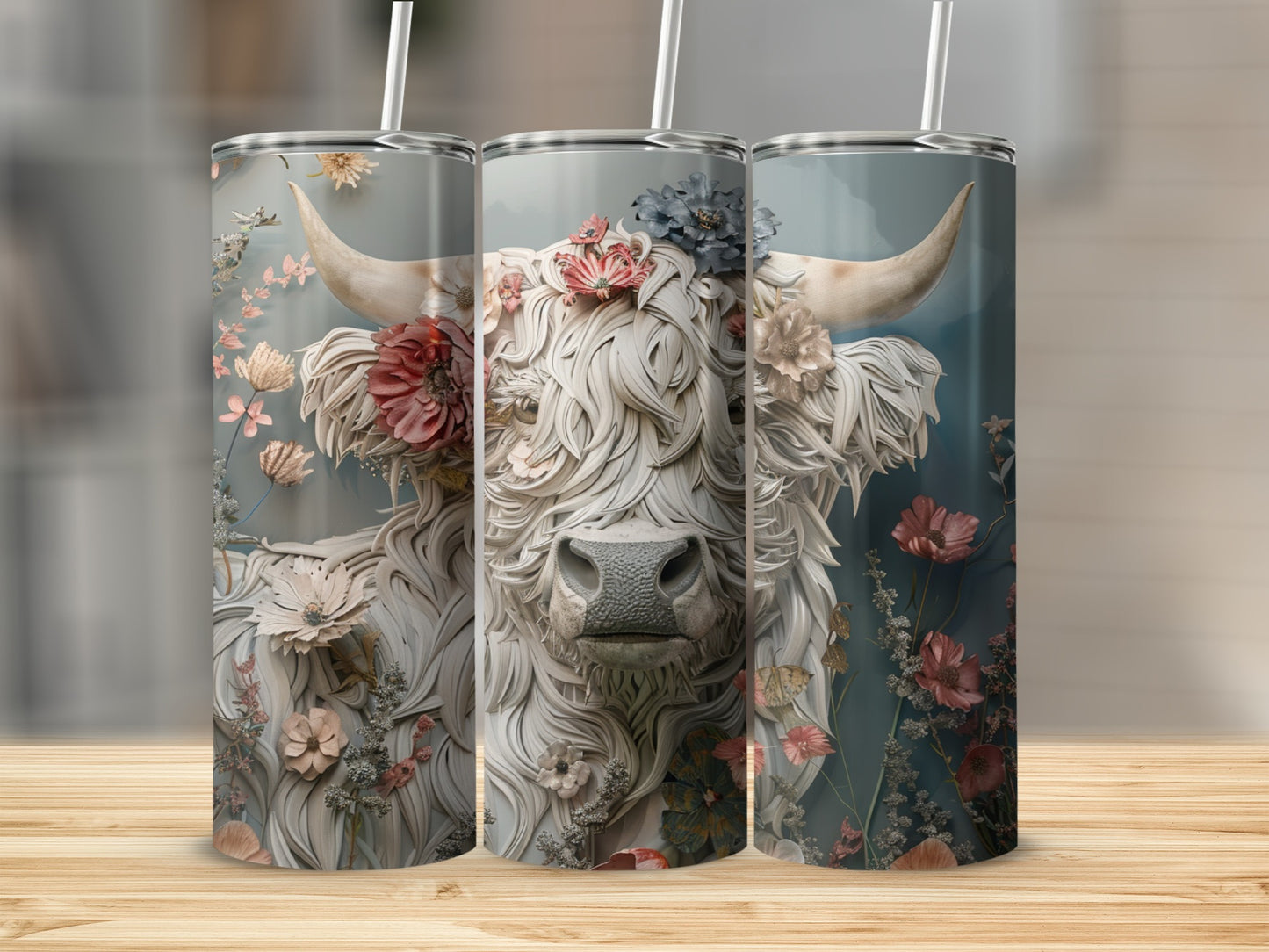 Floral Highland cow artwork on three stainless steel tumblers.