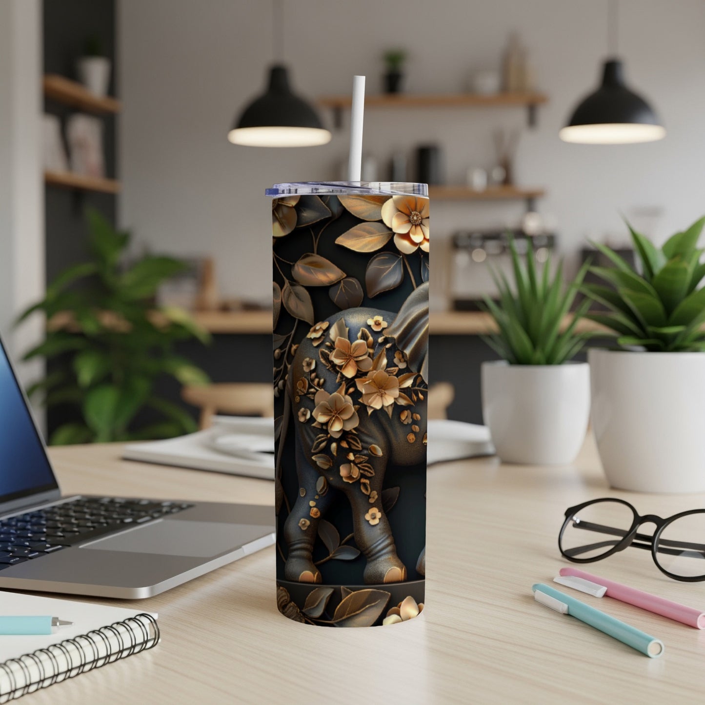 Black elephant tumbler with gold floral embellishments, straw, on desk.